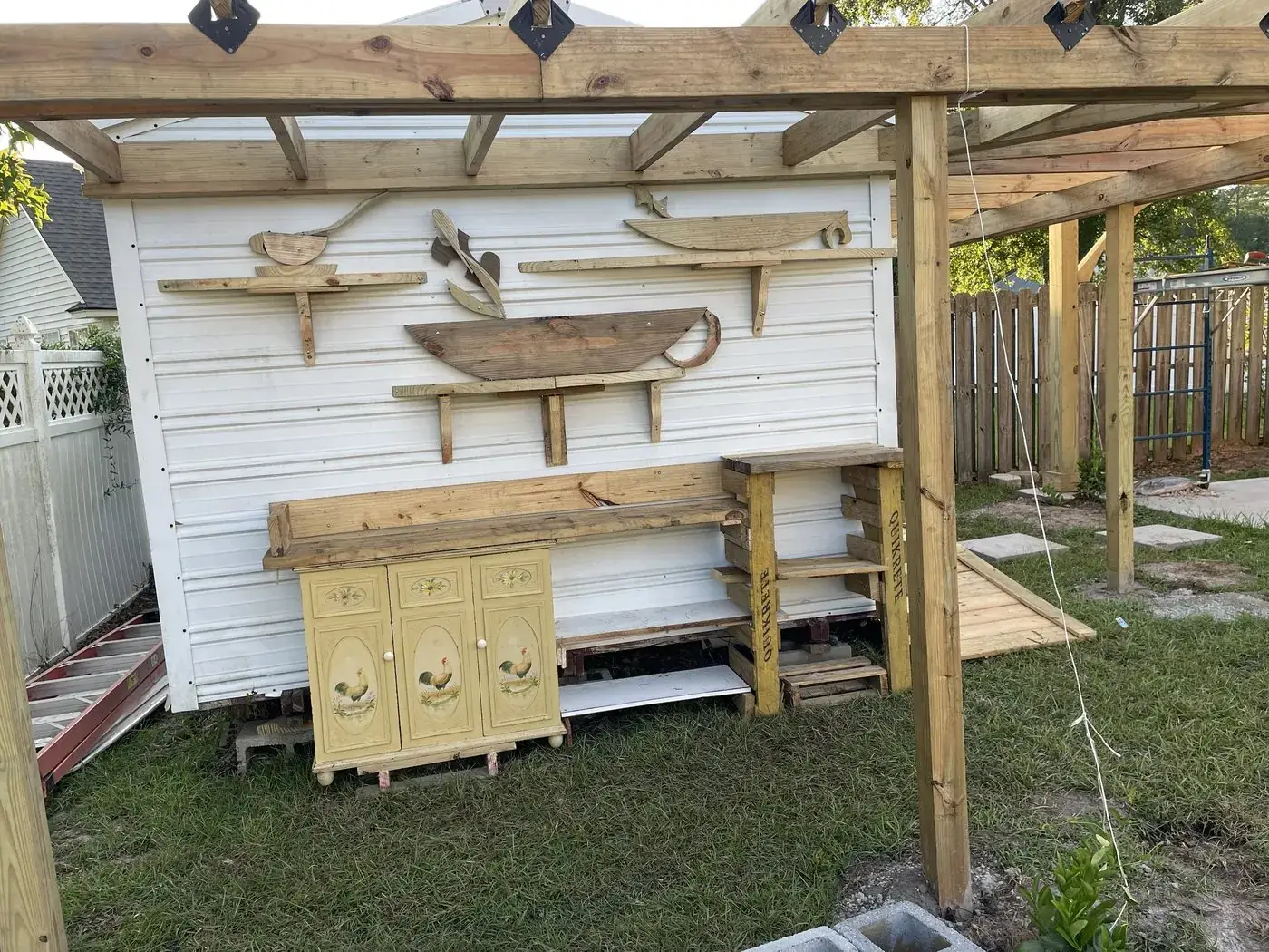 Backyard wall with carved boat shelves mounted under a pergola
