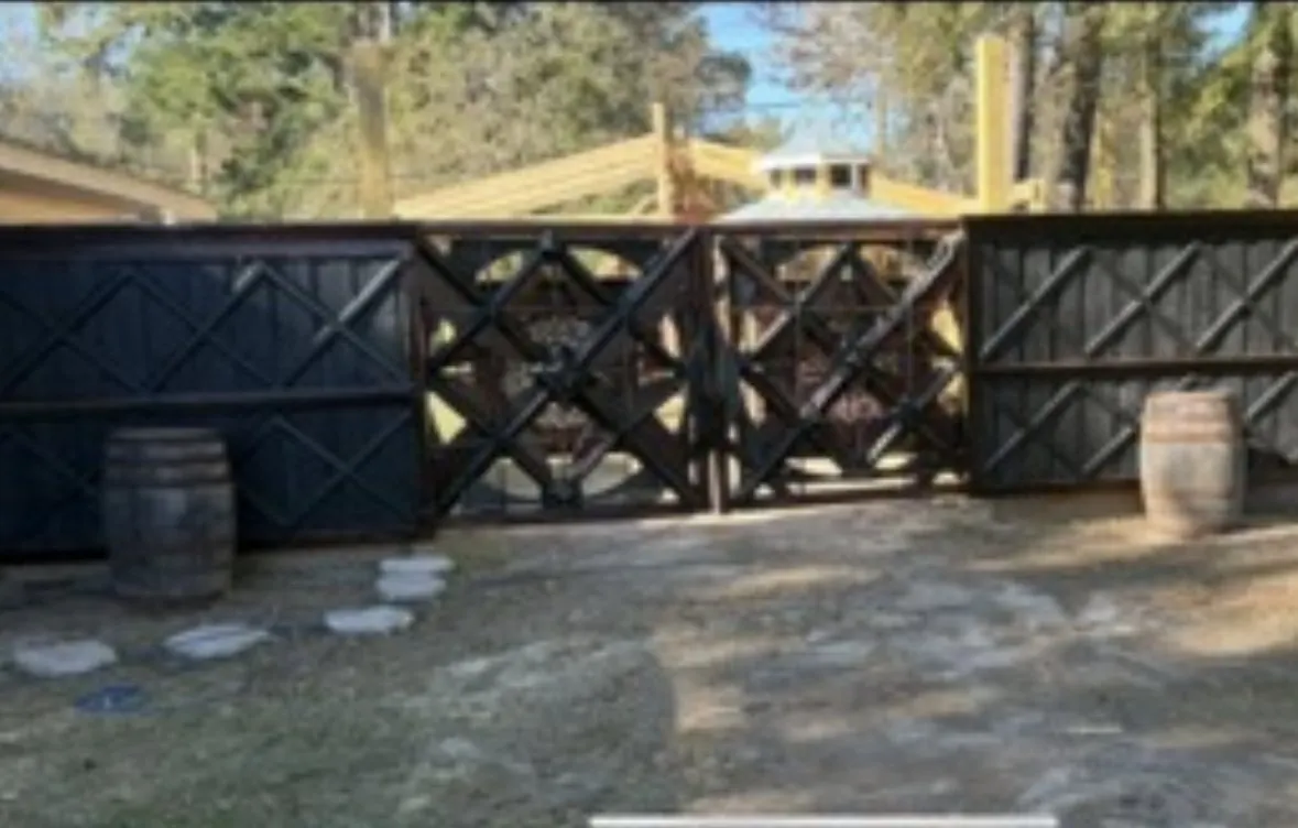 Dark stained fence run with a geometric X-pattern gate section between solid panels