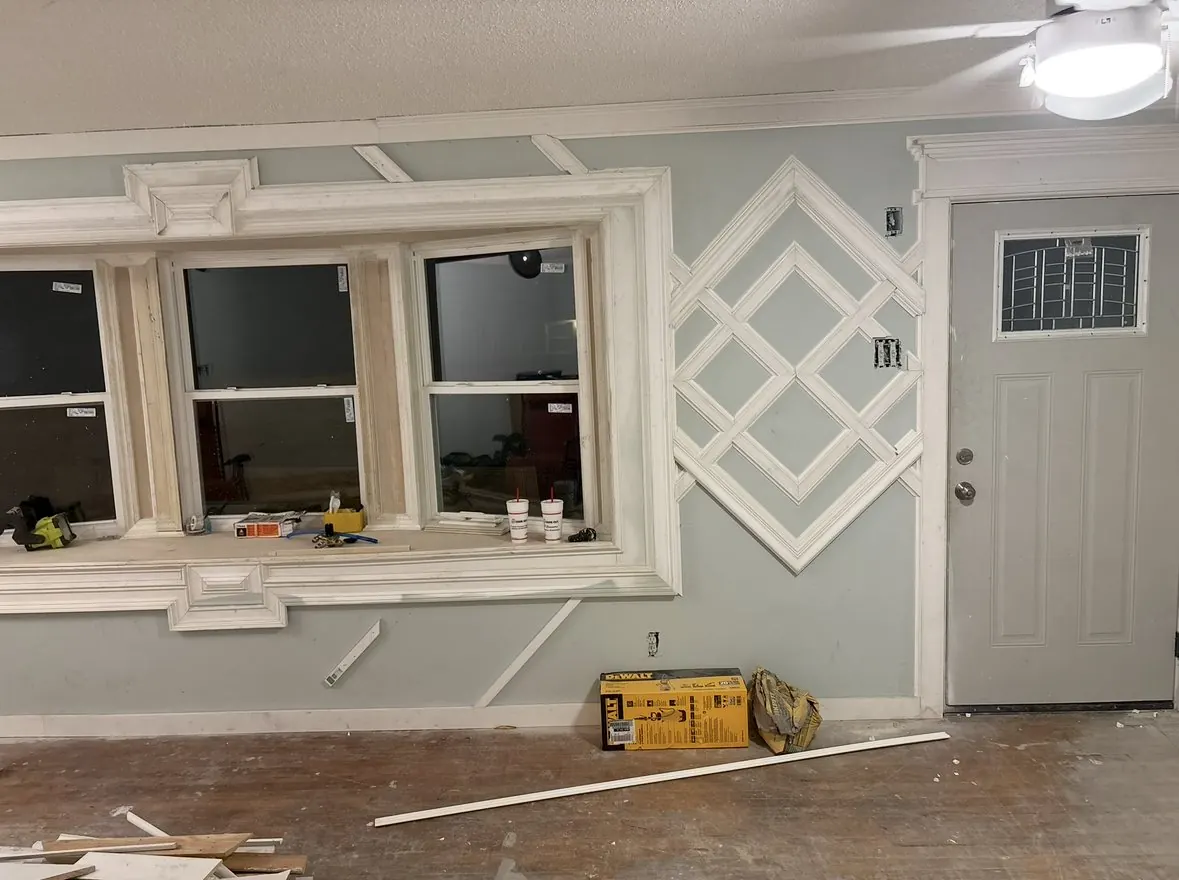 Interior wall with layered diamond trim work beside a cased window and door
