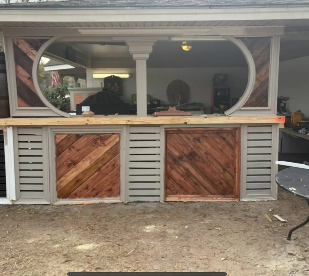 Built-in outdoor bar with oval openings and diagonal plank panels
