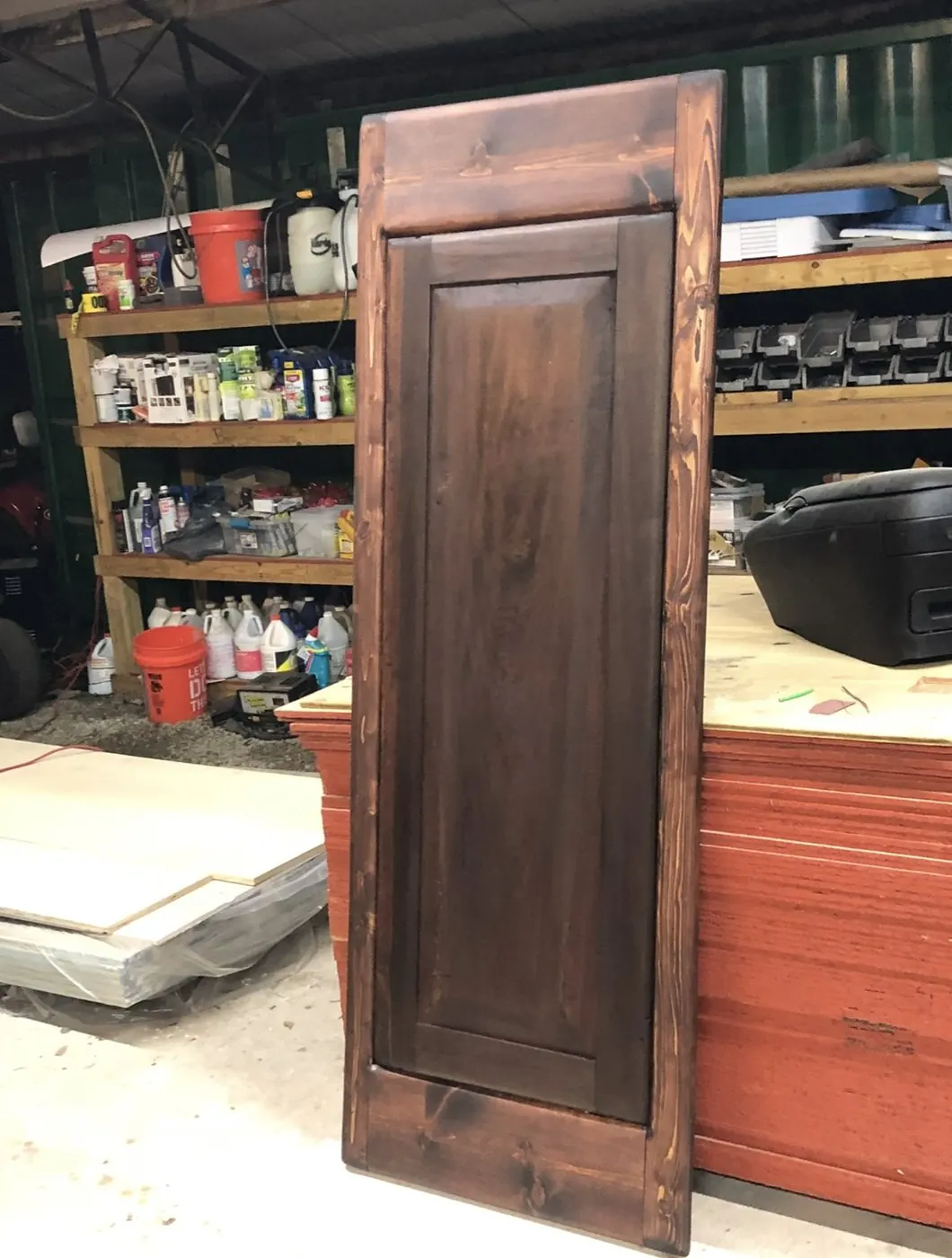 The finished door stained, standing against the bench in the shop