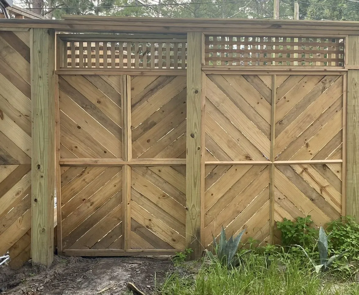 Run of chevron fence panels with lattice topper beside the house