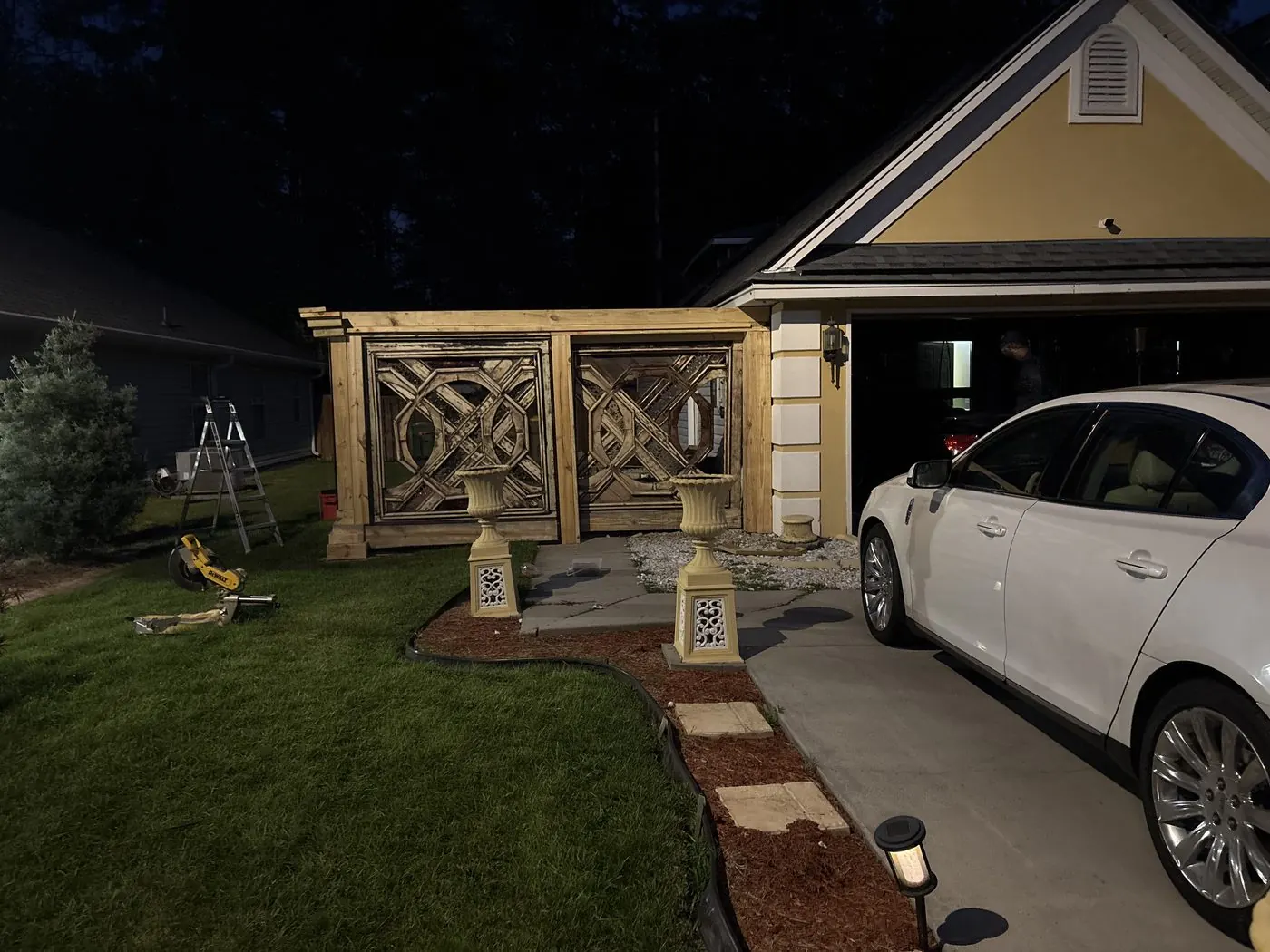Unstained gate panels set in their frame beside the house at dusk