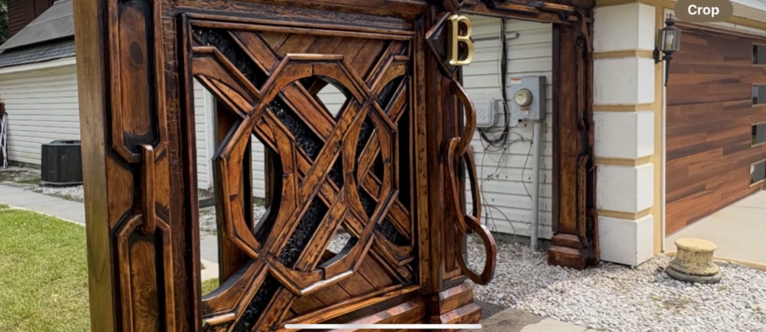 Close detail of the brass monogram and carved gate frame