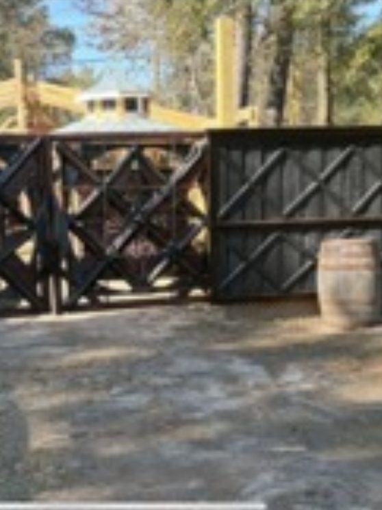 Dark geometric driveway gates flanked by whiskey barrels