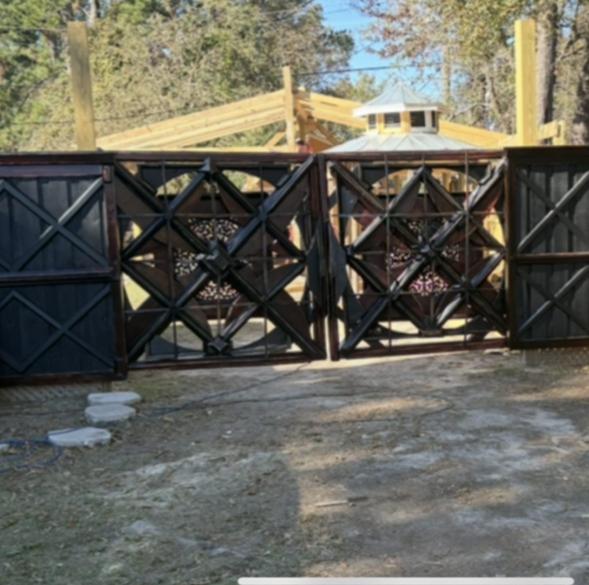 Pair of dark stained geometric entry gates with matching fence panels