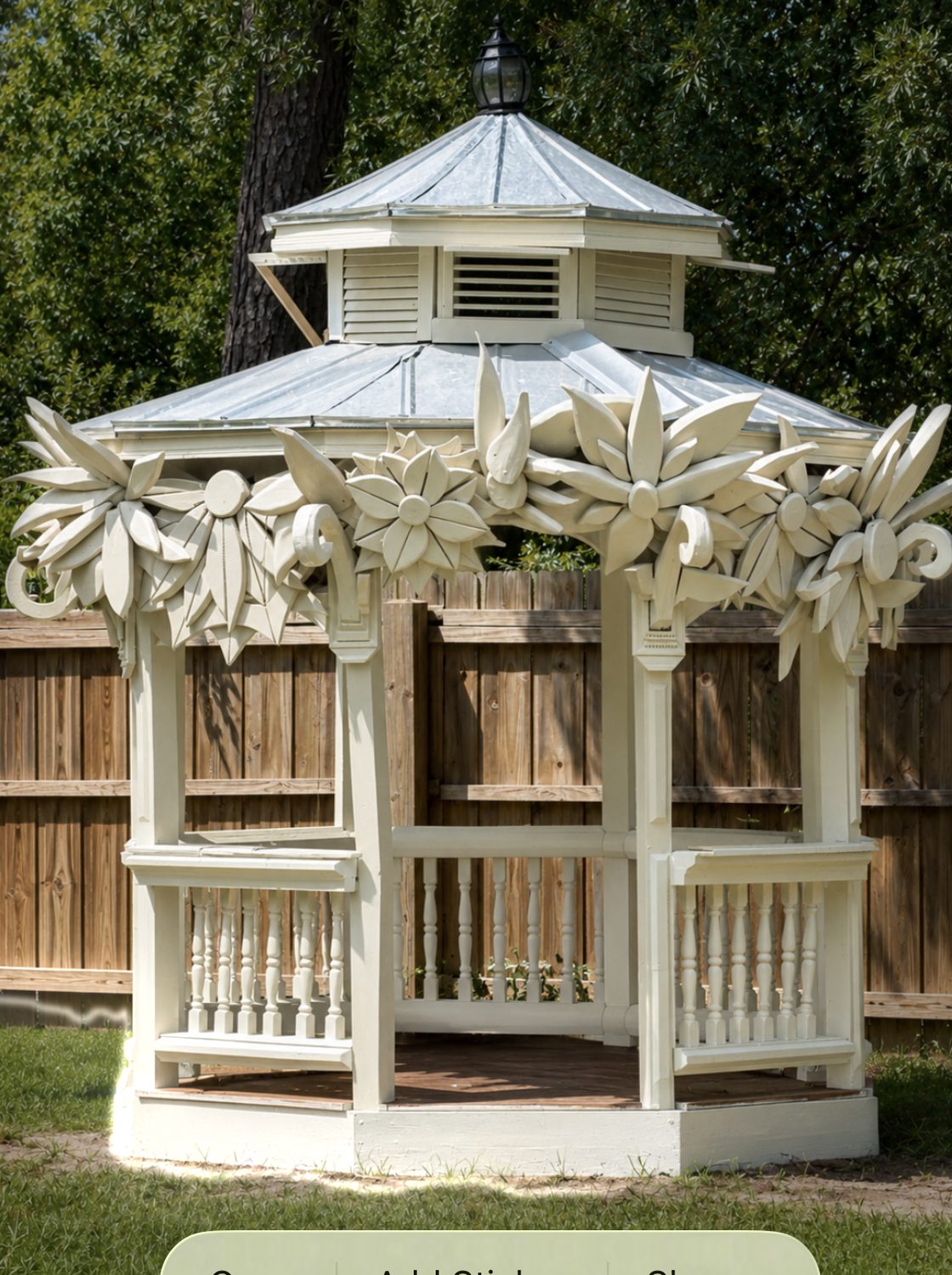 White gazebo with carved wooden floral garland wrapping the roofline