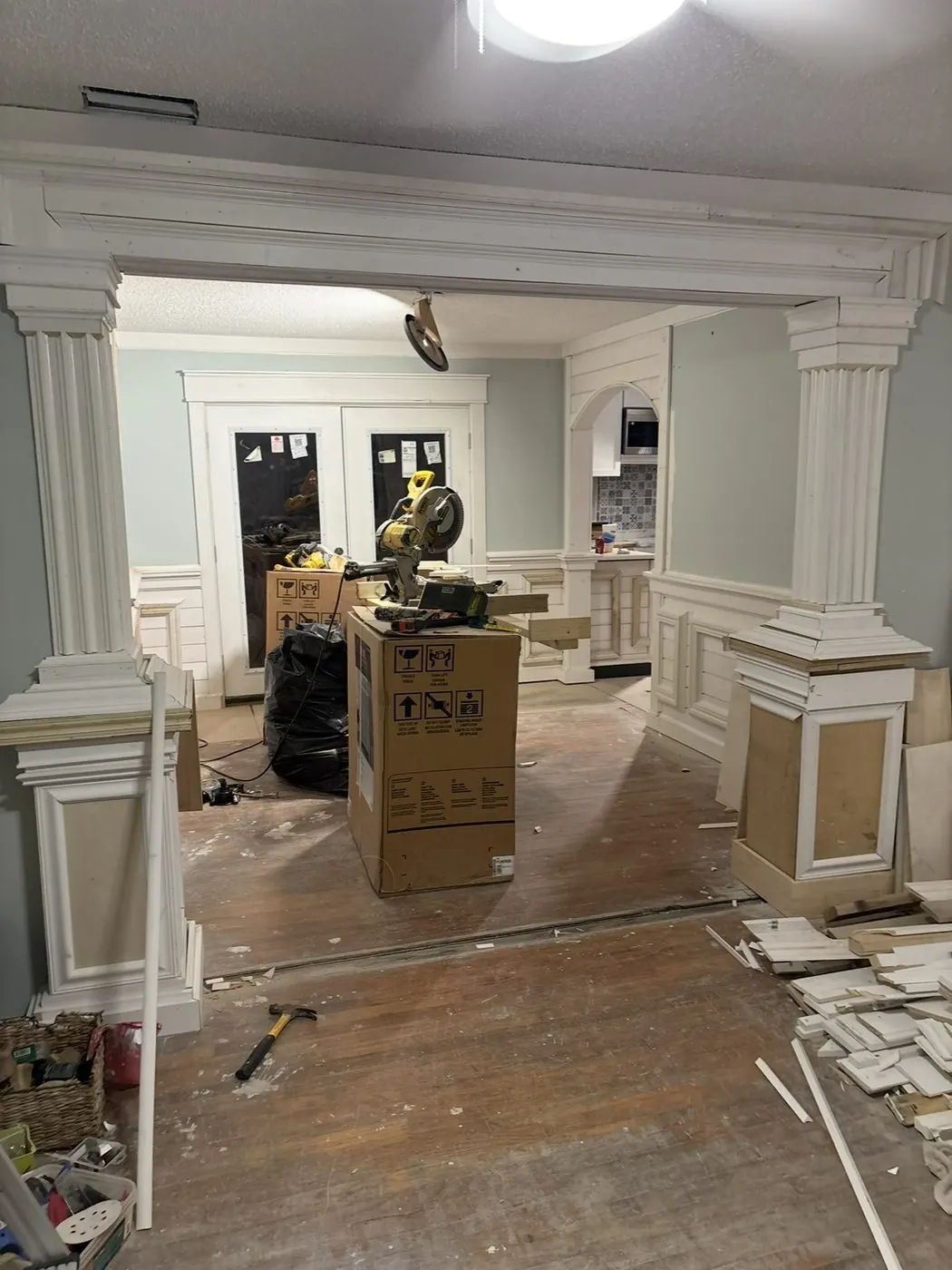 Fluted columns on paneled pedestals framing a room opening, in progress