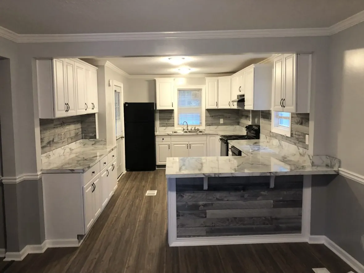 Finished kitchen with white cabinets, stone counters and a plank bar front