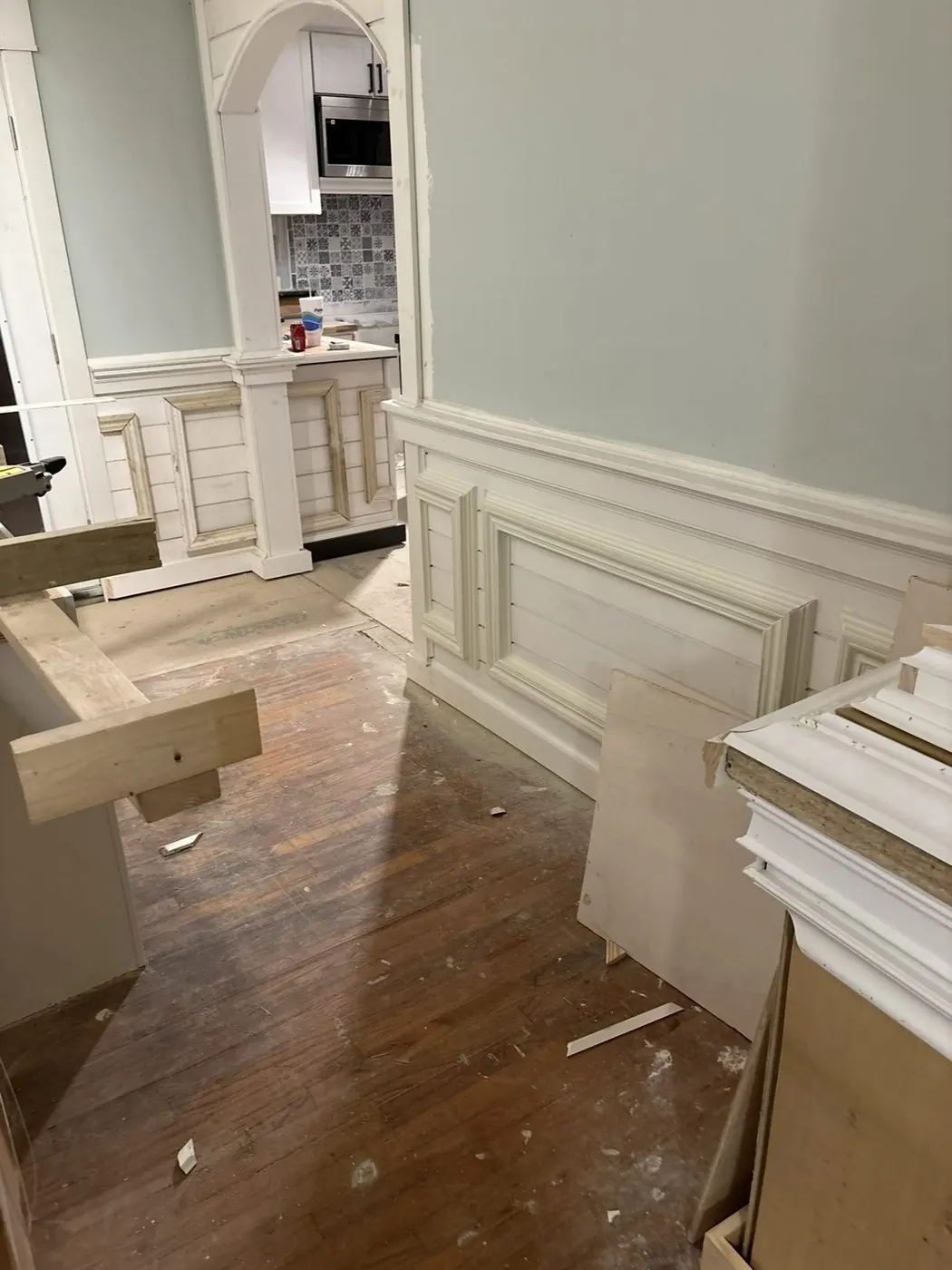 Raised-panel wainscot running along a wall, mid-install