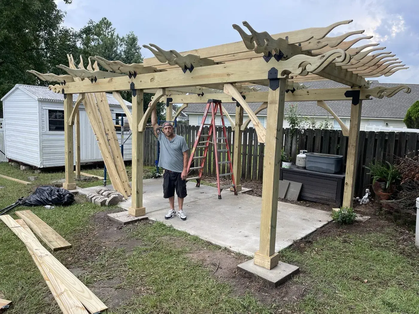 Pergola with rafters and carved wave tails installed, shown with a person for scale