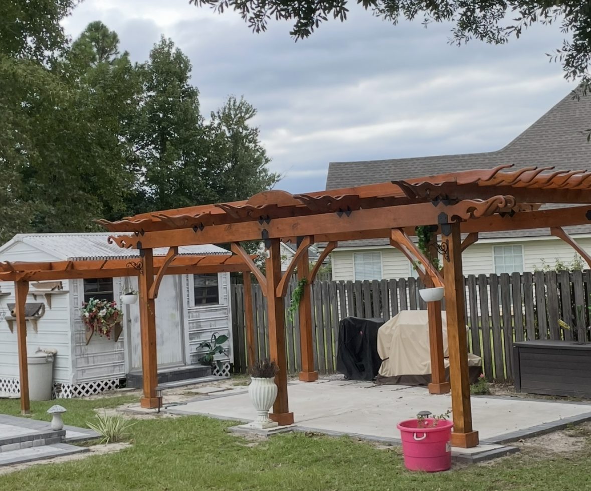 Stained cedar pergola with carved scrollwork rafter tails
