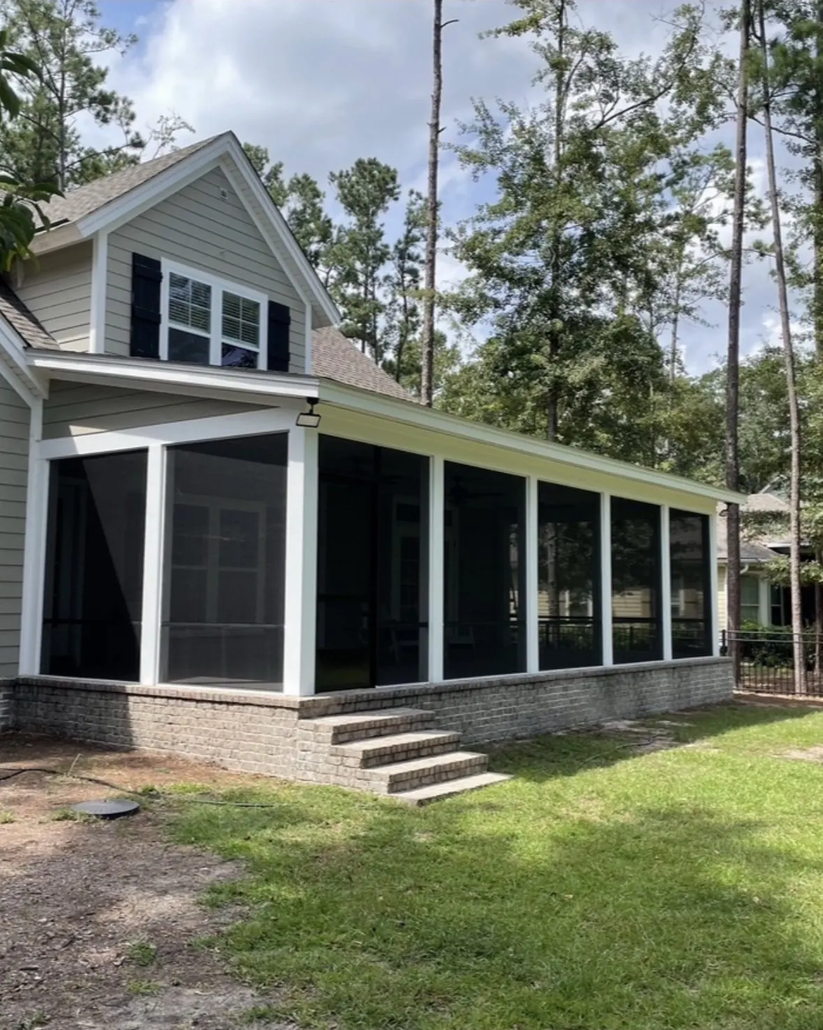 Screened porch with white posts on a brick knee wall and brick steps