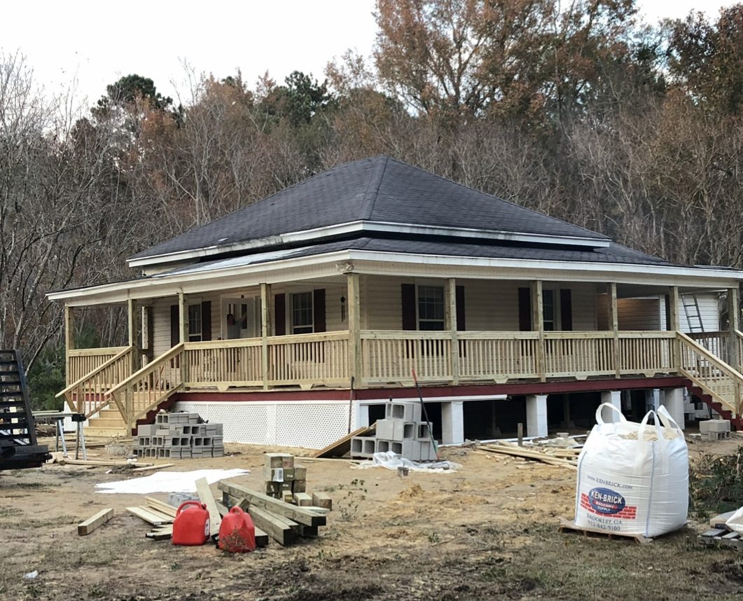 Wraparound porch with rails and stairs under construction