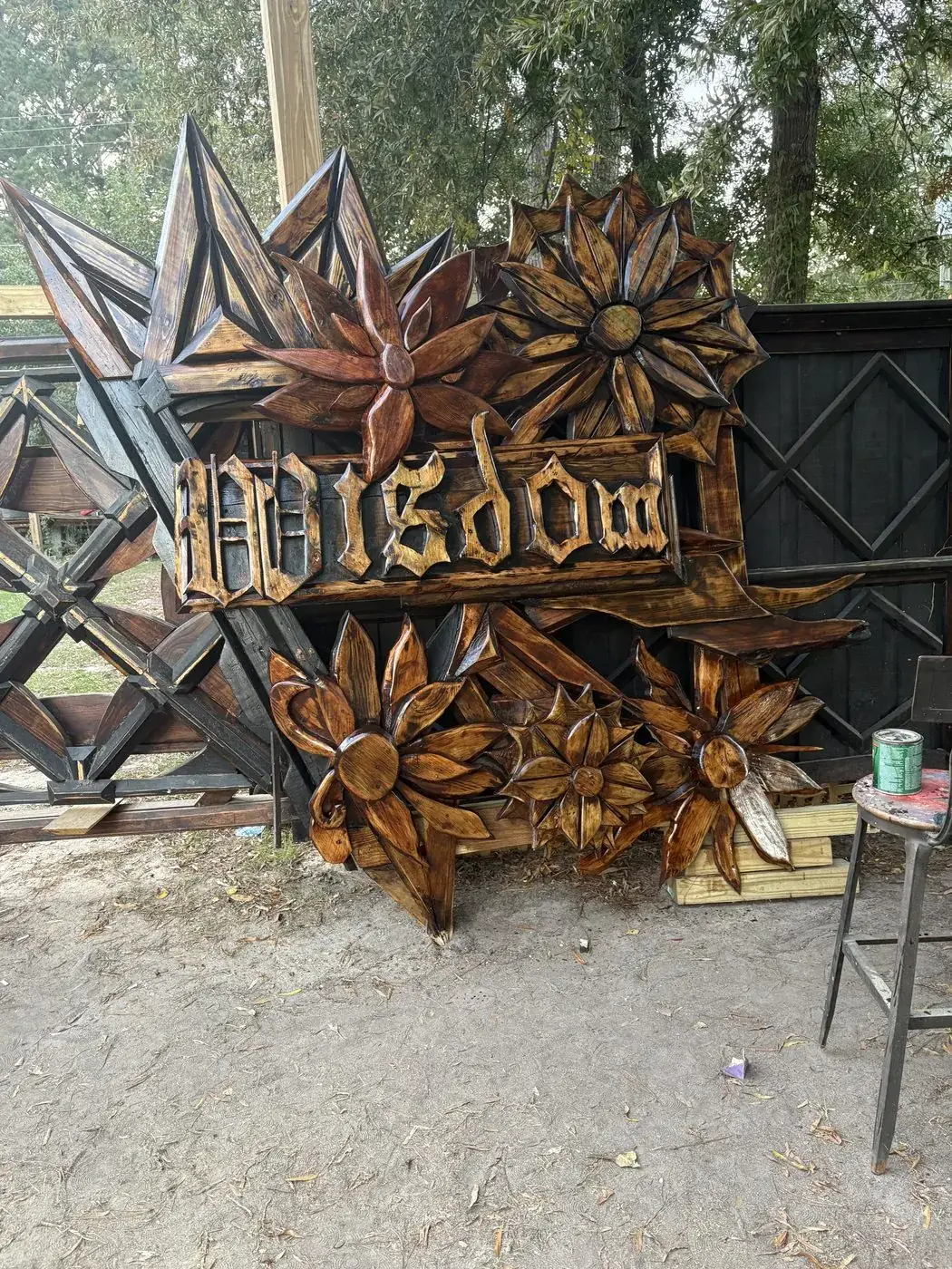 Carved WISDOM sign surrounded by layered wooden flowers and spikes